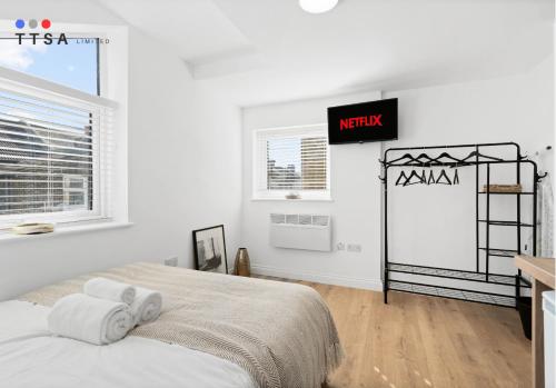 a white bedroom with a bed and a clock on the wall at TTSA - Studio - Norwood Junction - B4 in Norwood