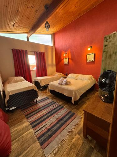 a room with two beds and red walls at Chalé Home Sul de Minas in Pouso Alegre