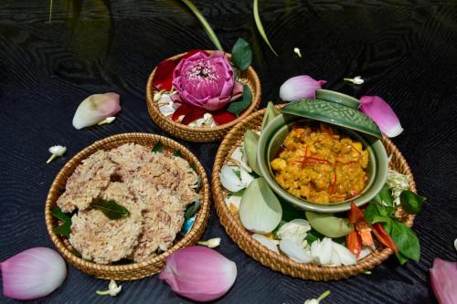 three bowls of food and flowers on a table at Dara Airport Hotel in Phnom Penh