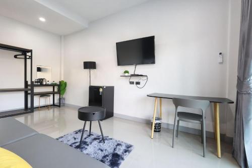 a living room with a table and a tv on the wall at Hillside Premium Hotel in Ban Huai Chiat