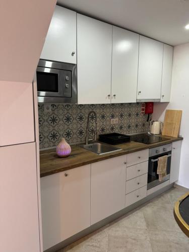 a kitchen with white cabinets and a sink and a microwave at Casa Rosa in Setúbal