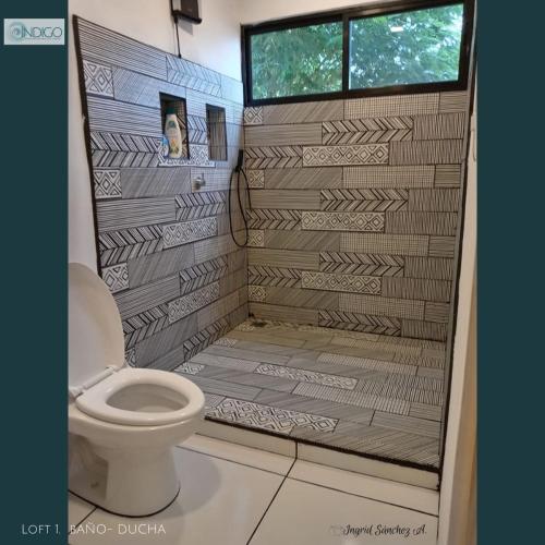 a bathroom with a toilet and a window at Hermoso apartamento tipo loft in Nicoya