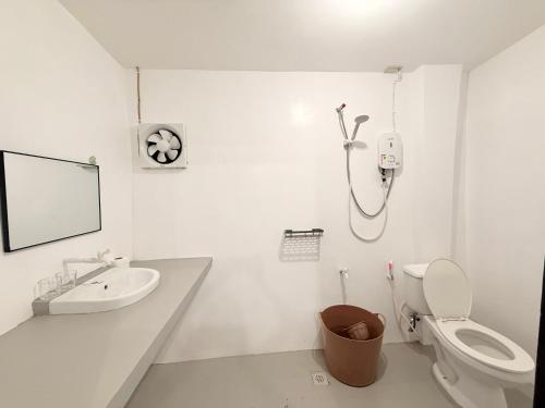 a white bathroom with a toilet and a sink at Inn Convenience in Coron