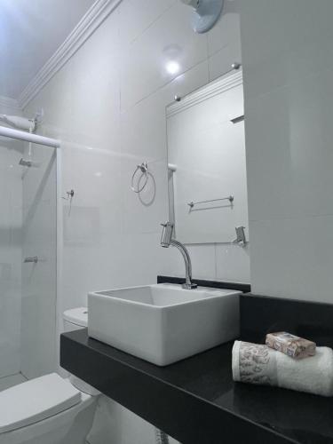 a white bathroom with a sink and a toilet at Salt Lake Suítes in Arraial do Cabo