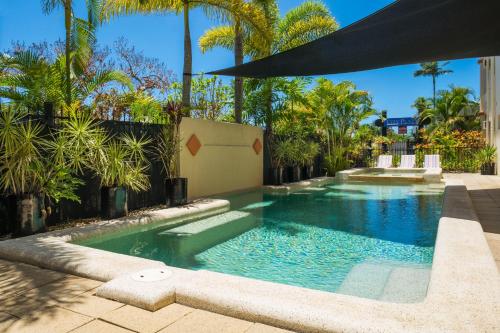 una piscina en un patio con palmeras en City Plaza Apartments, en Cairns