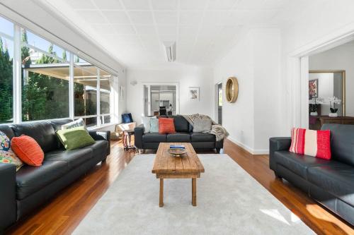 a living room with two black couches and a coffee table at The Spacious & Elegant Vacation Haven - Glenside in Glenunga