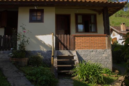 a small house with a wooden staircase leading to the door at Pousada da Carmem in Visconde De Maua