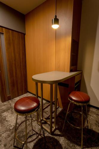 a table and two stools in a room at Hotel Sundays Amami in Amami