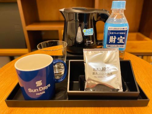 a tray with cups and a coffee maker on a table at Hotel Sundays Amami in Amami