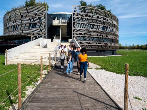 a group of people walking on a boardwalk in front of a building at Cottage in Semur-en-Auxois in Forest Retreat in Semur-en-Auxois