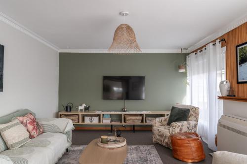 a living room with two couches and a tv at Cosy Ulverstone Getaway with Parking in Ulverstone