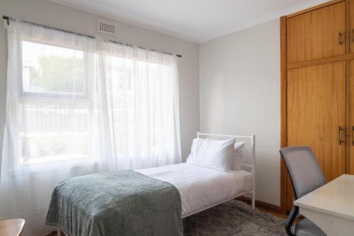 a white bedroom with a bed and a window at Cosy Ulverstone Getaway with Parking in Ulverstone