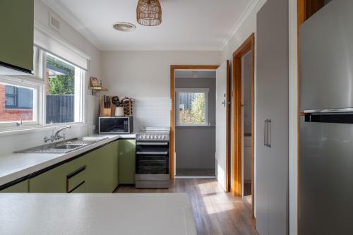 a kitchen with green and white counters and a refrigerator at Cosy Ulverstone Getaway with Parking in Ulverstone