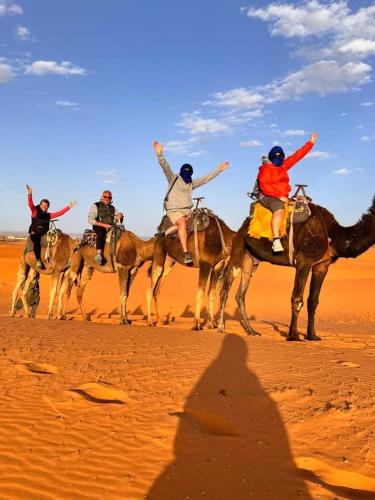 a group of people riding on horses in the desert at Khadija Desert Camp in Merzouga