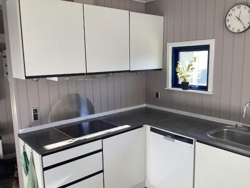 a kitchen with white cabinets and a sink and a clock at 8 person holiday home in Nakskov in Nakskov