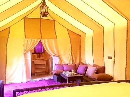 a room with a bed and a couch and a table at Khadija Desert Camp in Merzouga