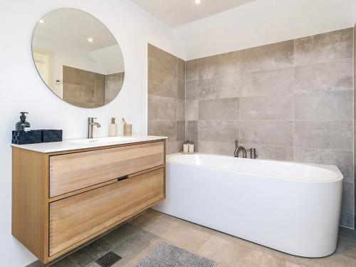 a bathroom with a tub and a sink and a mirror at 5 star holiday home in Liseleje in Liseleje