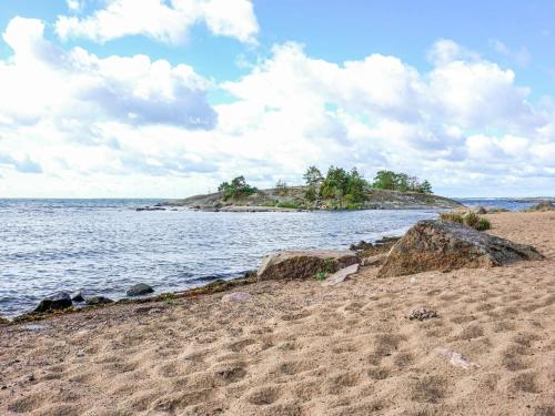 a sandy beach with a small island in the water at 6 person holiday home in OSKARSHAMN in Oskarshamn