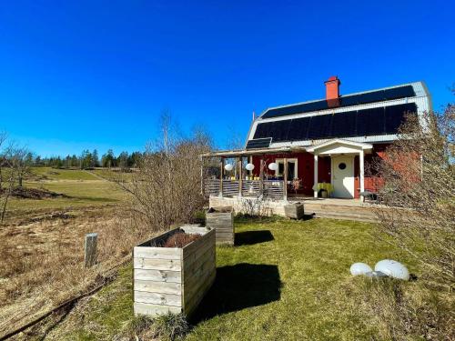 a red house with a black roof in a field at 6 person holiday home in VIMMERBY in Vimmerby