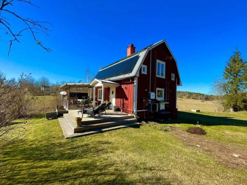 a red barn with a porch and a deck at 6 person holiday home in VIMMERBY in Vimmerby