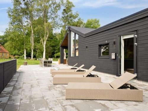 a black house with chairs and a patio at 5 star holiday home in Glesborg in Glesborg