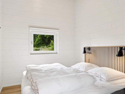 a white bedroom with a bed with a window at 5 star holiday home in Glesborg in Glesborg