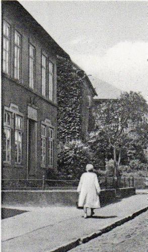 a woman walking down a street next to a building at Fewo Hein Da Sein in Ahrensbök