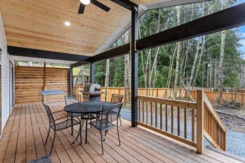 a wooden deck with a table and chairs on it at Glacier Run, Hot Tub, Sauna,Movie Theater, WiFi, EV in Ashford