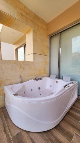 a large white tub in a room with a large mirror at Con jacuzzi privado, laguna y Paddle board in Cartagena de Indias