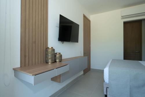 a bedroom with a bed and a tv on a wall at Con jacuzzi privado, laguna y Paddle board in Cartagena de Indias