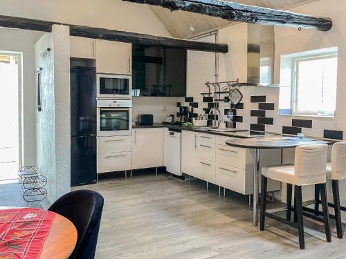 a kitchen with white cabinets and a table with chairs at 4 person holiday home in ANDERSLÖV in Anderslöv