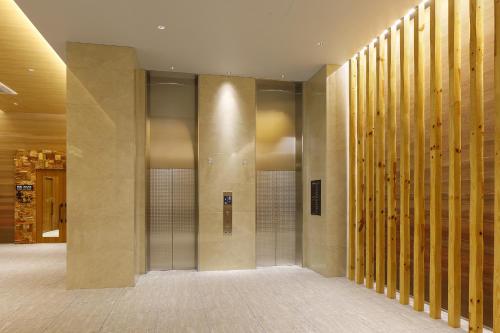 a hallway with a row of elevators in a building at Hotel Sundays Amami in Amami