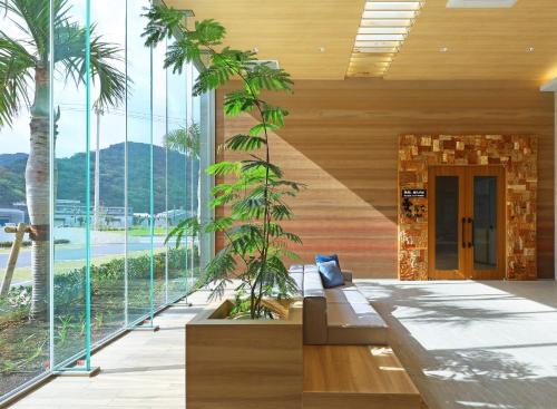 a living room with palm trees and a couch at Hotel Sundays Amami in Amami
