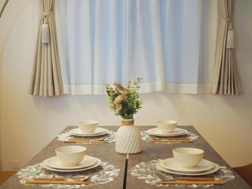 a table with plates and cups and a vase with flowers at 桜の川65 池袋駅C6口 8分 2-10人丨Ikebukuro JR Line C6 Exit 8 minutes 2-10 people in Tokyo