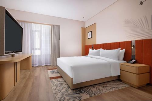 a bedroom with a large bed and a flat screen tv at Hilton Garden Inn Harbin Haxi in Harbin