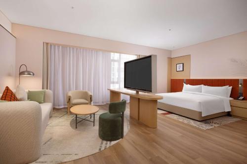 a hotel room with a bed and a flat screen tv at Hilton Garden Inn Harbin Haxi in Harbin