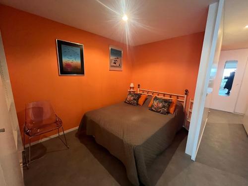 - une chambre aux murs orange avec un lit et une chaise dans l'établissement Appartement T2 au centre d'Arcachon avec balcon vue bassin et parking - FR-1-374-51, à Arcachon