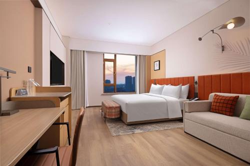 a hotel room with a bed and a couch at Hilton Garden Inn Harbin Haxi in Harbin