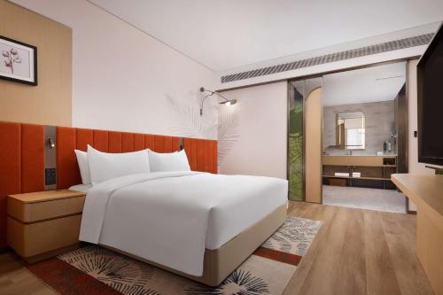 a bedroom with a large white bed and a bathroom at Hilton Garden Inn Harbin Haxi in Harbin