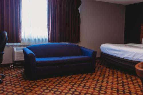 a hotel room with a blue chair and a bed at Americinn by Wyndham Appleton Downtown in Appleton