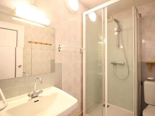 La salle de bains est pourvue d'un lavabo et d'une douche avec une porte en verre. dans l'établissement Appartement F2 au pied des pistes avec balcon, parking et local à skis - FR-1-415-62, à Le Mont-Dore