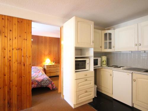- une cuisine avec des placards blancs et un lit dans une chambre dans l'établissement Appartement F2 de 38m² au pied des pistes du Mont-Dore, 6 couchages, local à skis - FR-1-415-115, à Le Mont-Dore