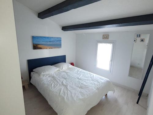 - une chambre avec un lit doté d'une tête de lit bleue et d'une fenêtre dans l'établissement Maison lumière près plage avec terrasse, 2 chambres, BBQ, parking, linge fourni - FR-1-778-20, à Saint-Georges-dʼOléron