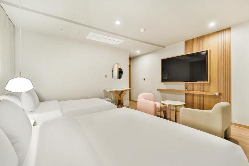 a hotel room with a bed and a flat screen tv at Grandis Hotel in Busan