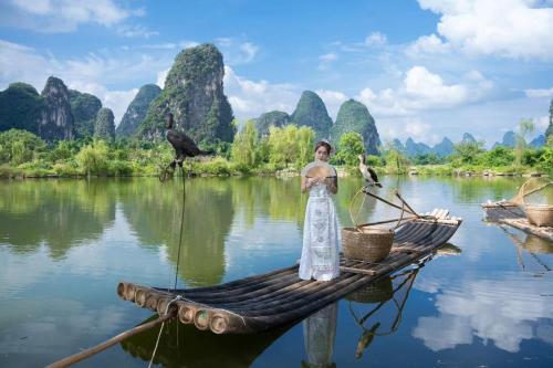 a woman standing on a bamboo raft on a river at Yangshuo Hidden Dragon Villa in Yangshuo