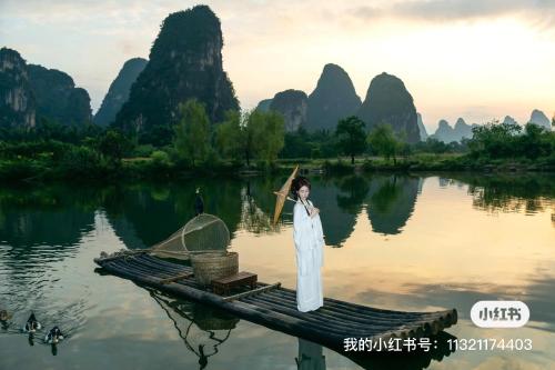 a woman standing on a boat in the water at Yangshuo Hidden Dragon Villa in Yangshuo