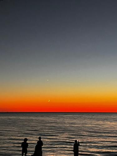three people standing on the beach watching the sunset at Boho apartment studio in Batumi