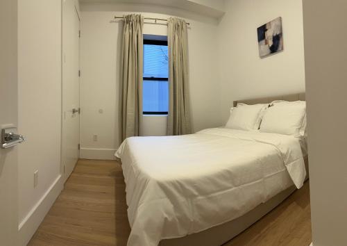a bedroom with a white bed and a window at Modern, New 3 bed, 2 bath Apt near Manhattan in Jersey City