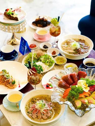 a table with plates of food and bowls of food at SANDALS AQUILA HOTEL in Bao Loc