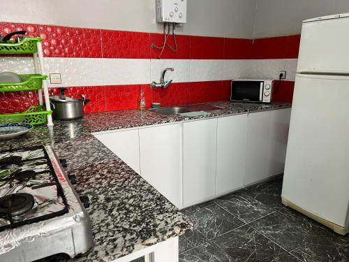 Una cocina con gabinetes blancos y una pared roja. en Younes residence, en Asilah